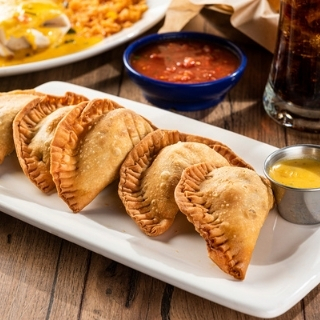 Empanadas: Handmade pastries filled with mixed cheese & seasoned ground beef. Served with our Signature Queso.