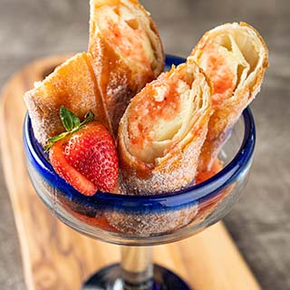 Strawberry Cheesecake Chimis Golden fried cheesecake-filled chimichangas and strawberry puree.